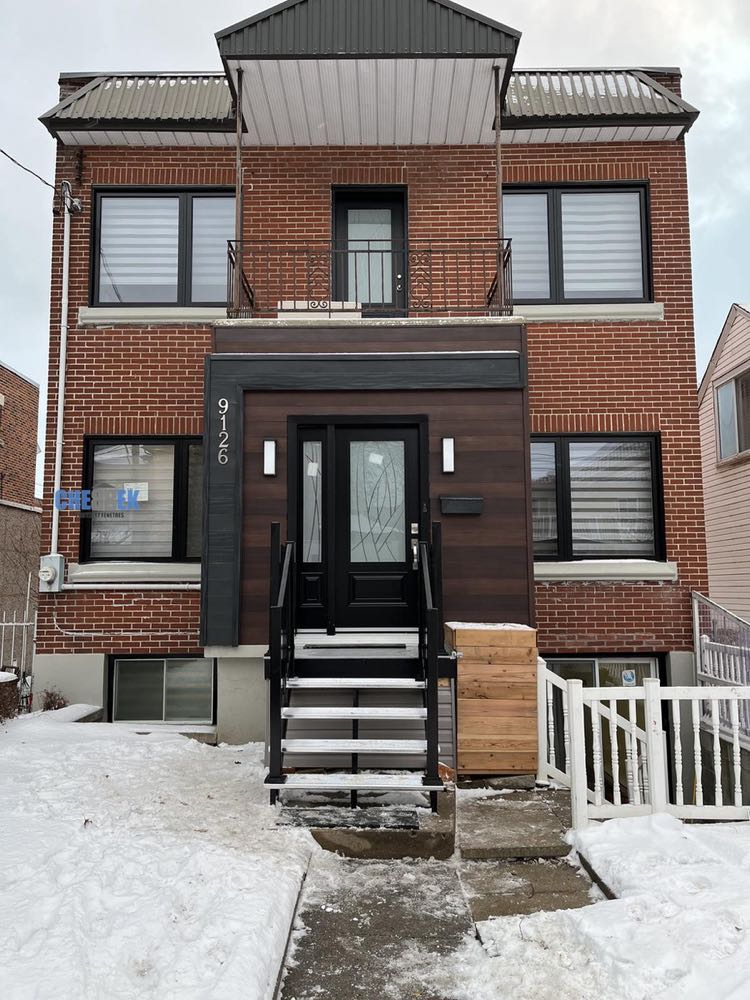 Duplex résidentiel avec porte d'entrée noire, balcon et auvent en aluminium installés par CHEBBEK Portes et Fenêtres à Montréal