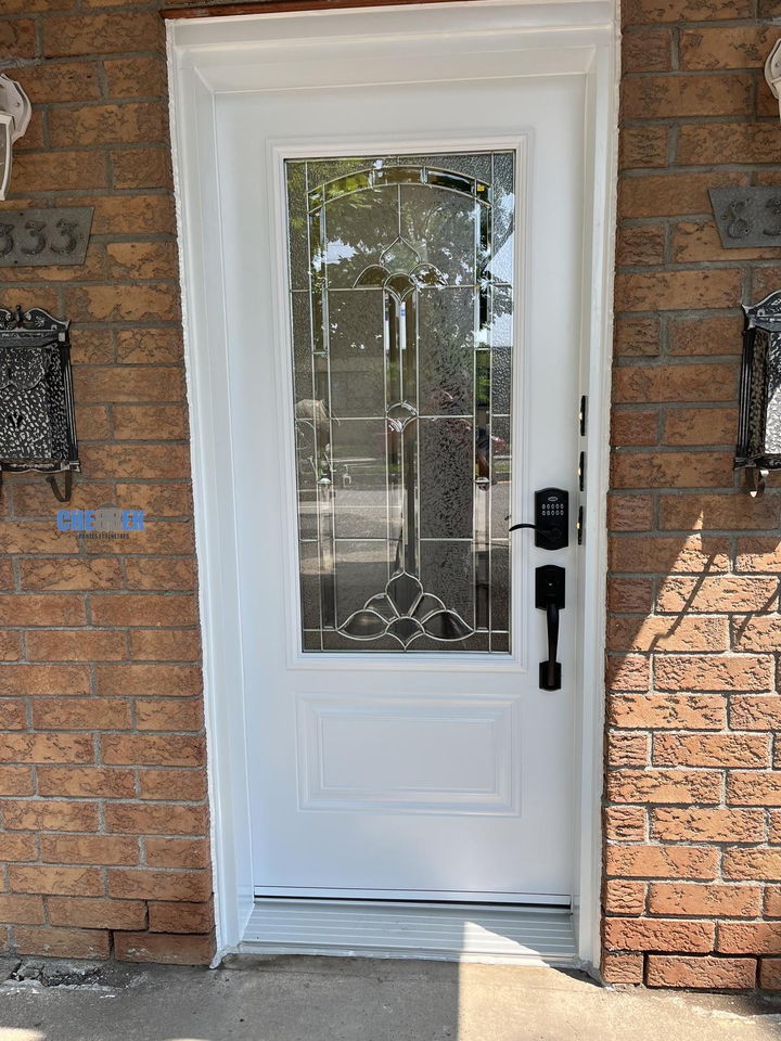White entry door with decorative glass on a brick front
