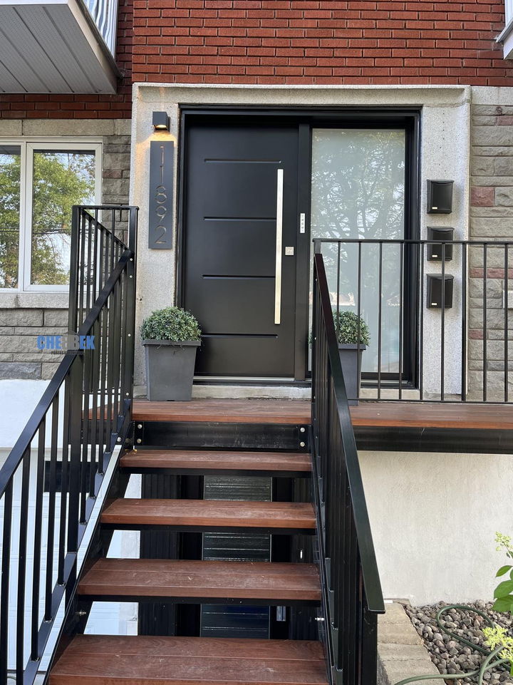 Rampe noire le long d'un escalier menant à une porte d'entrée