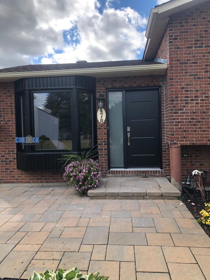 Fenêtres noires et porte d'entrée sur un bungalow de brique
