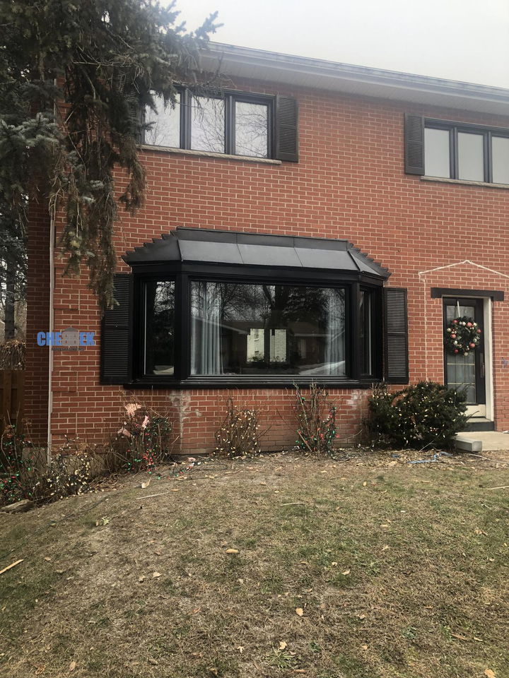 Fenêtre en baie noire sur une maison de brique rouge